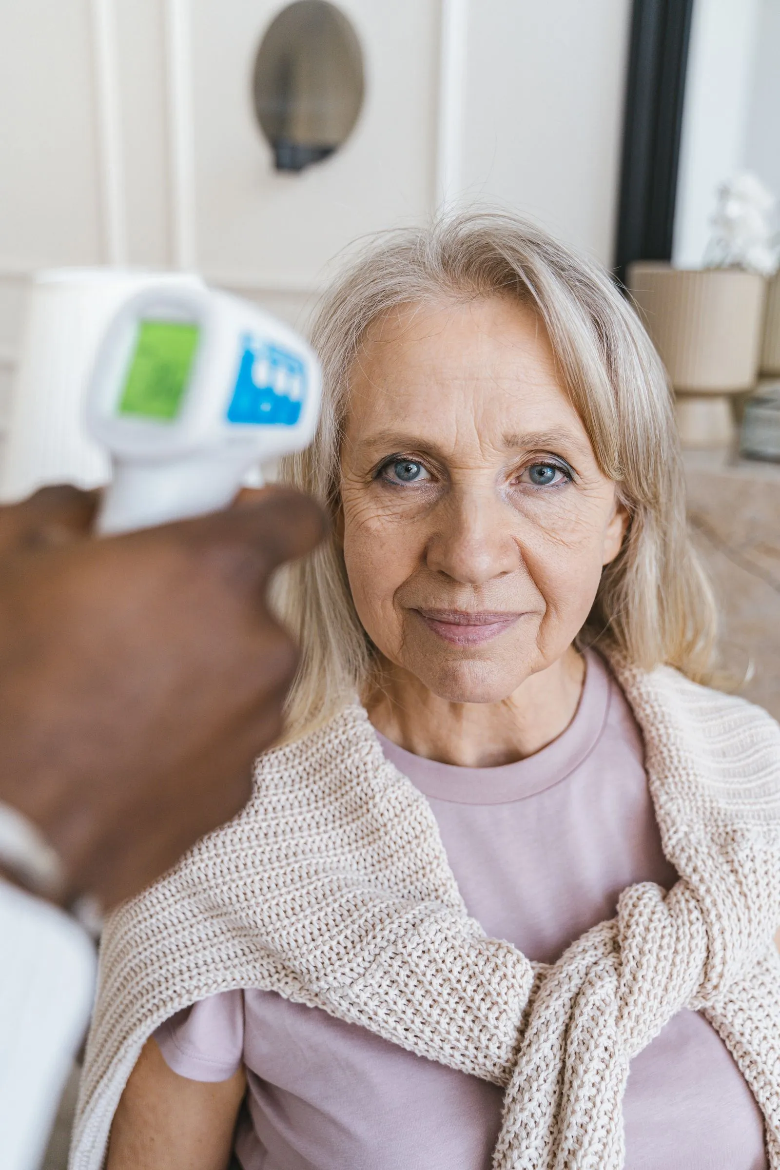 A caregiver gently checking on an elderly woman at home